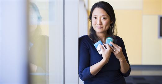 A woman in a blue shirt holds two packs of cigarettes.
