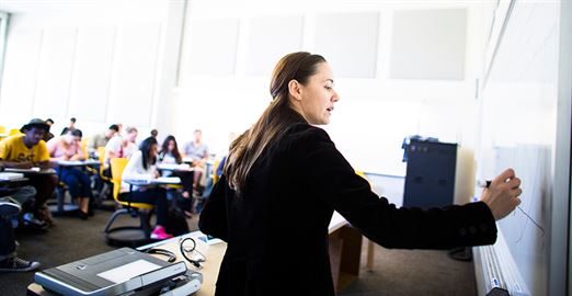 A female teacher writing on a white board.