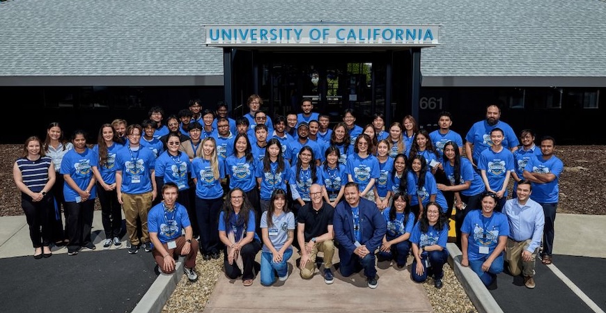 A group of students wearing blue shirts is lined up in front of the University of California facility in Livermore