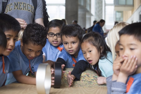 Visiting students watch wheel races as they learn about angular momentum.