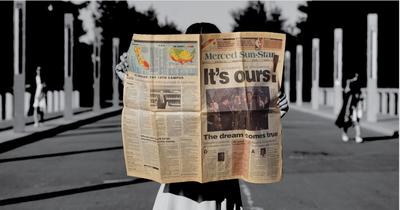 A student holds a copy of the Merced Sun-Star, with a large headline proclaiming 