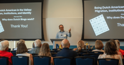 Man in front of a room presenting to an audience that is seated