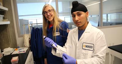 Professor Patti LiWang and student Adesh Johal, holding a syringe and a test tube, stand in a lab at UC Merced.