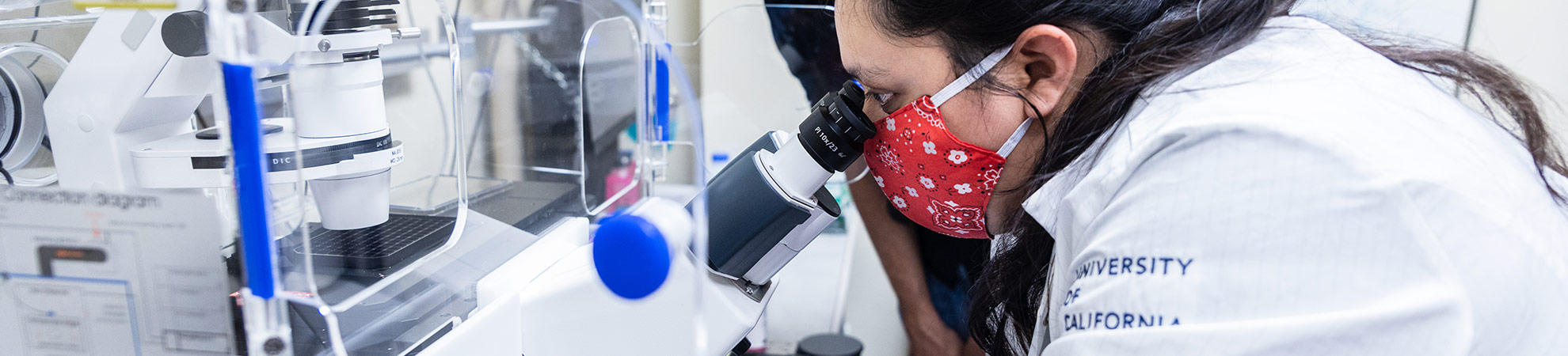 female student looking into a microscope in a medical setting